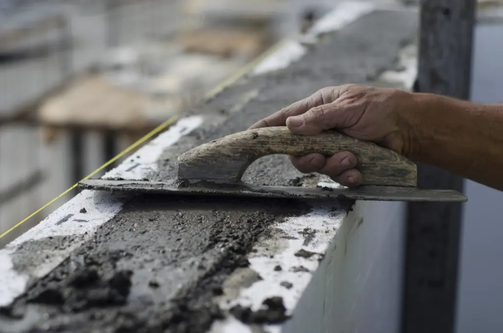Hand finishing concrete along the top of an ICF wall with a trowel