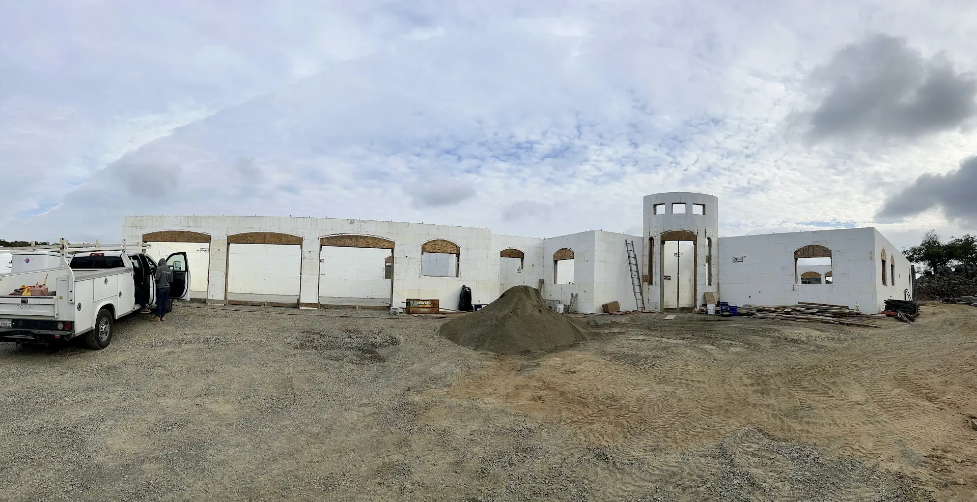 Panoramic view of an ICF building shell with arched openings and a round entry tower