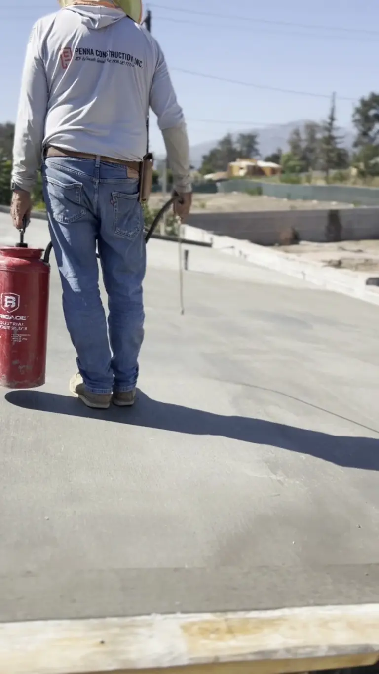 Crew member applying curing compound to a finished concrete roof deck